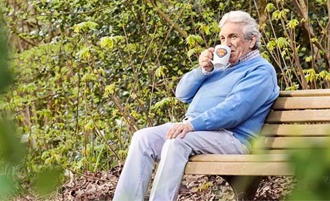Oudere meneer geniet van zijn kopje koffie in een eigen herbruikbare beker