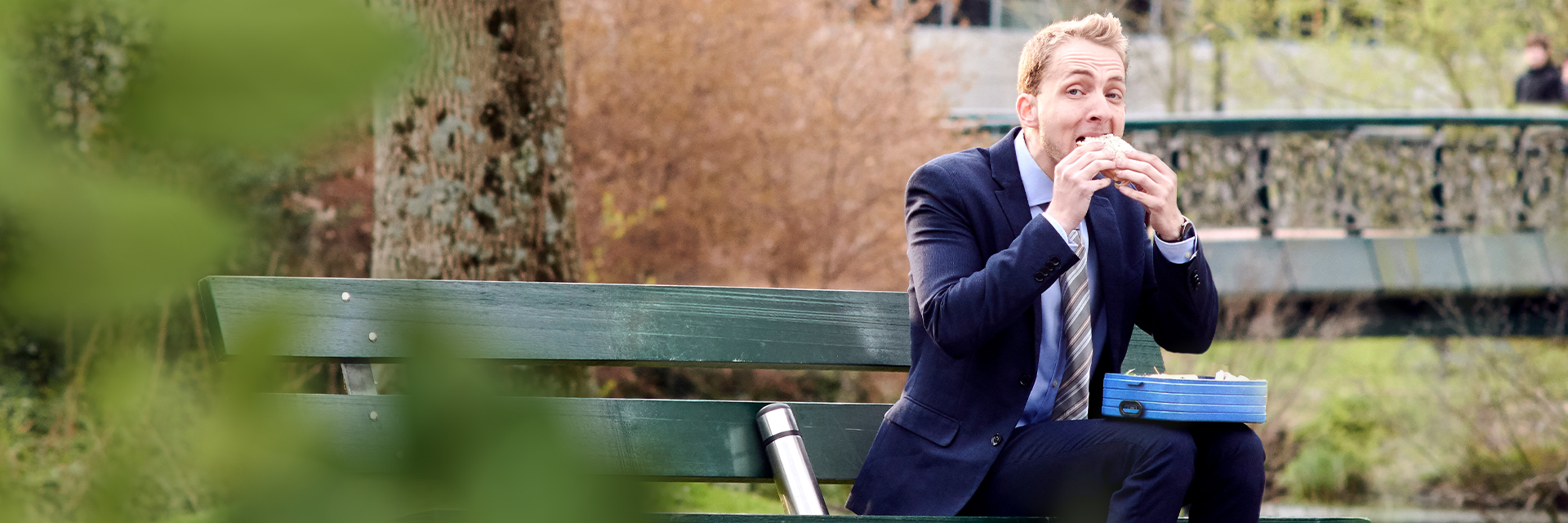 Man in pak zit op bankje zijn lunch te eten uit een broodtrommel