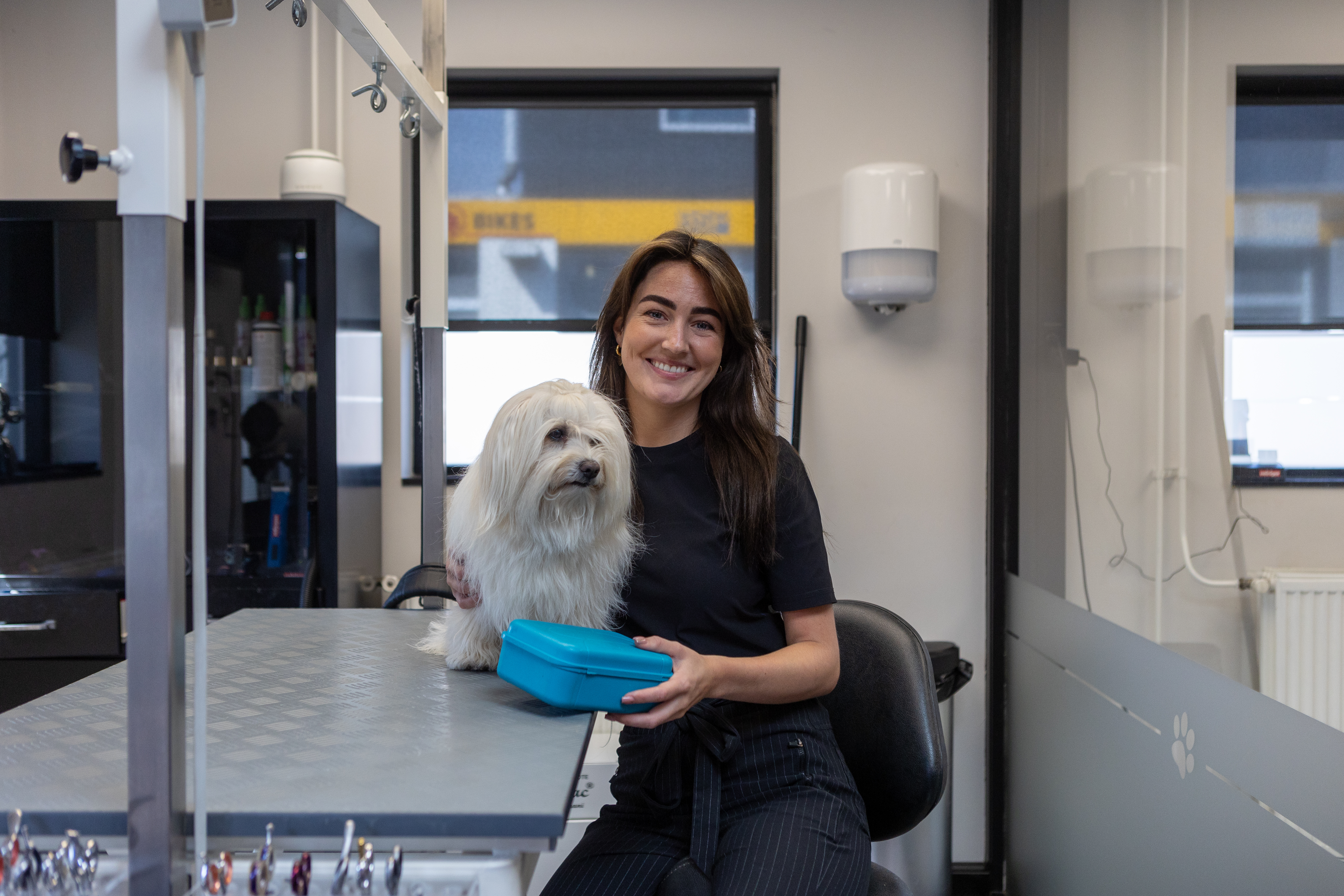 Vrouw met bruin haar poseert op de foto met haar hondje en een herbruikbare lunchbox