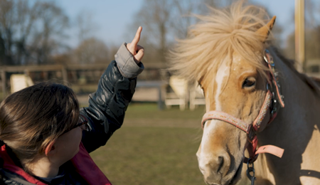 Meisje aait haar pony bij zorgstal Helvoirt