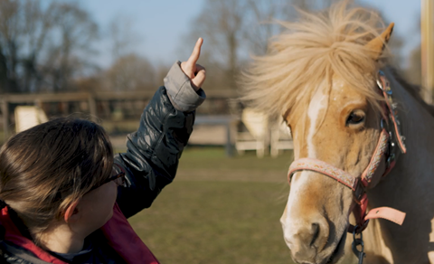 Meisje aait haar pony bij zorgstal Helvoirt