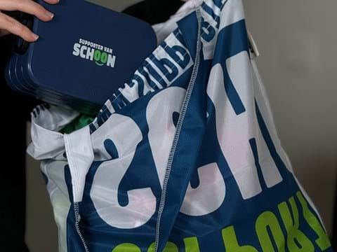 Een herbruikbare tas van stof waar een broodtrommel in wordt gestopt