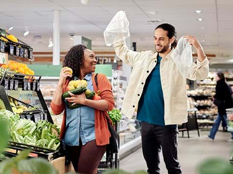 Man en vrouw in de supermarkt, man houdt verszakjes vast